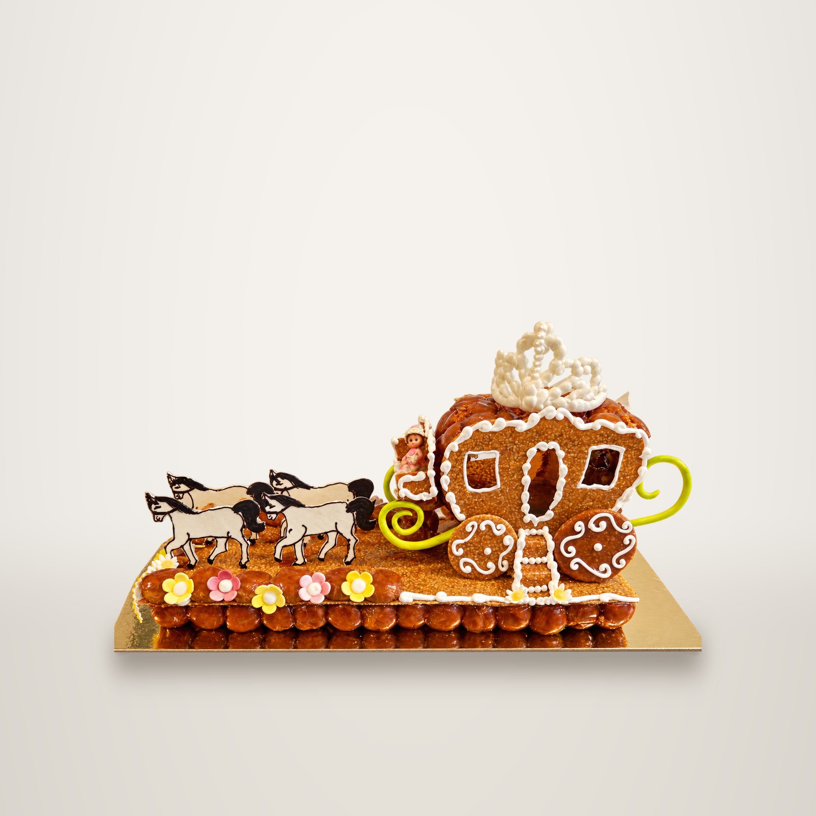 Pièce montée en forme de carrosse de princesse décoré de glaçage blanc, tiré par quatre chevaux blancs sur une base de petits choux ornée de fleurs en sucre.