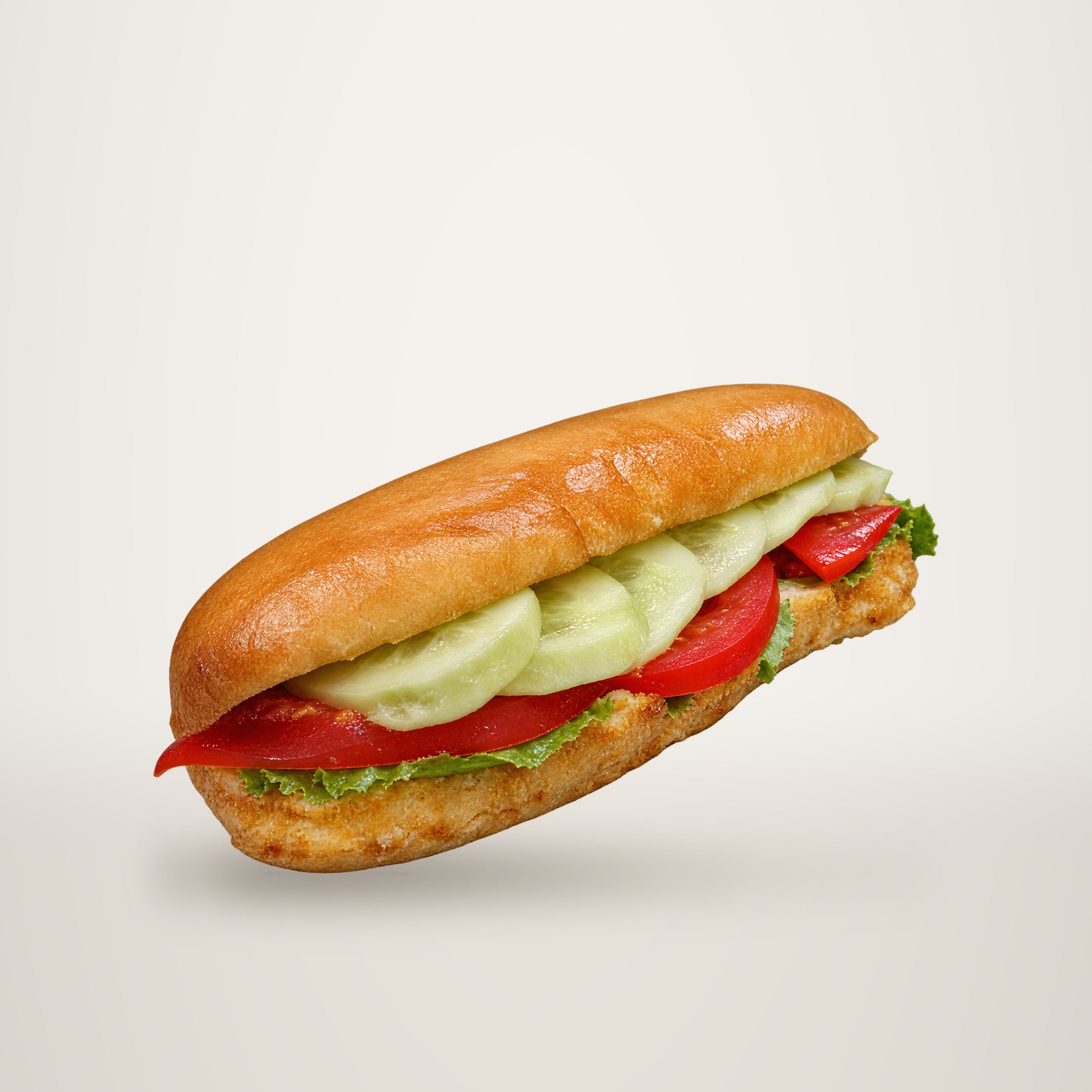 Un petit pain garni de tranches de tomate et d'une crème claire, posé sur une surface grise métallique.